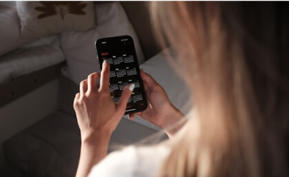 Person using a smartphone calendar app, viewed from behind.